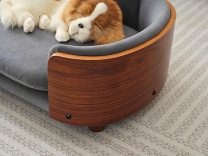 Detail of curved solid wood armrest on Scandinavian pet sofa, highlighting elegant design and velvet upholstery.