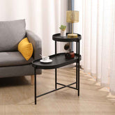 Black side table with decorative items next to a gray sofa with yellow pillow in a living room setting.
