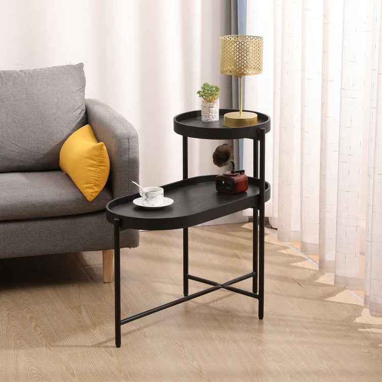 Black side table with decorative items next to a gray sofa with yellow pillow in a living room setting.