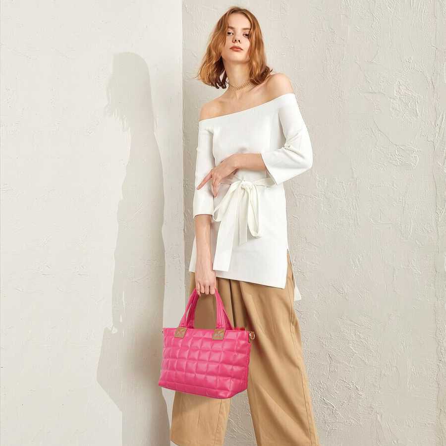 Woman holding a pink quilted handbag against a plain background