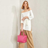 Woman holding a pink quilted handbag against a plain background