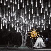 Cool white meteor shower lights hanging from a tree at night, with the solar panel and tubes