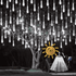 Cool white meteor shower lights hanging from a tree at night, with the solar panel and tubes