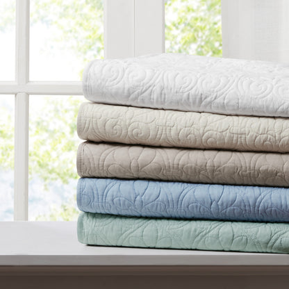 Stack of oversized quilted throws in multiple colors including white, beige, and blue, ideal for home bedding comfort and style.