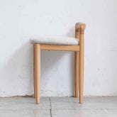 Wooden chair with a white cushion against a plain white wall.