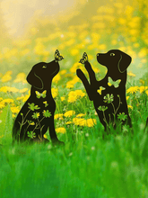 Black silhouette of two dogs with butterflies and flowers in a field of yellow flowers.
