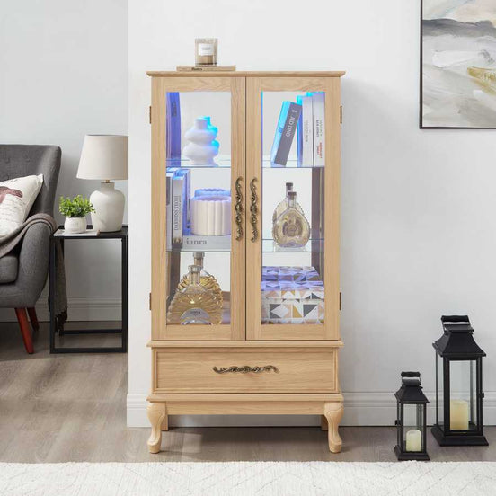 Lighted curio cabinet with adjustable glass shelves and drawer, showcasing collectibles in a modern living room setting.