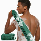 Man using a green mesh scrubber on his back with a white background