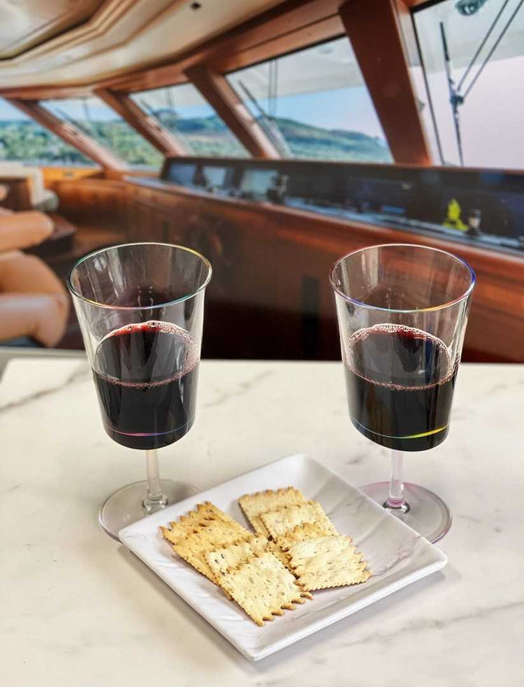 Two LeadingWare BPA-free plastic wine glasses with red wine beside crackers, perfect for boating or outdoor dining.