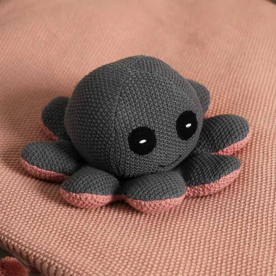 Close-up of knitted octopus plush toy with black eyes and pink-tipped tentacles