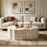 Bright living space with beige sofa, framed artwork, and a marble coffee table, illuminated by natural sunlight.
