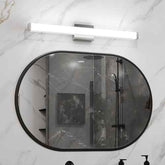 Bathroom with a large round mirror reflecting a shower area.