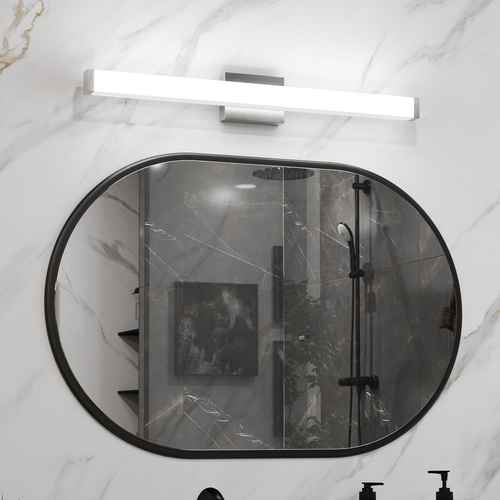 Bathroom with a large round mirror reflecting a shower area.