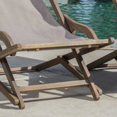 Wooden lounge chair with a gray cushion by a poolside