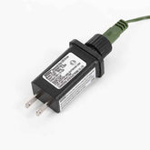 A black LED driver power adapter with a green cable, featuring a white label with technical specifications and two flat pins on a white background.