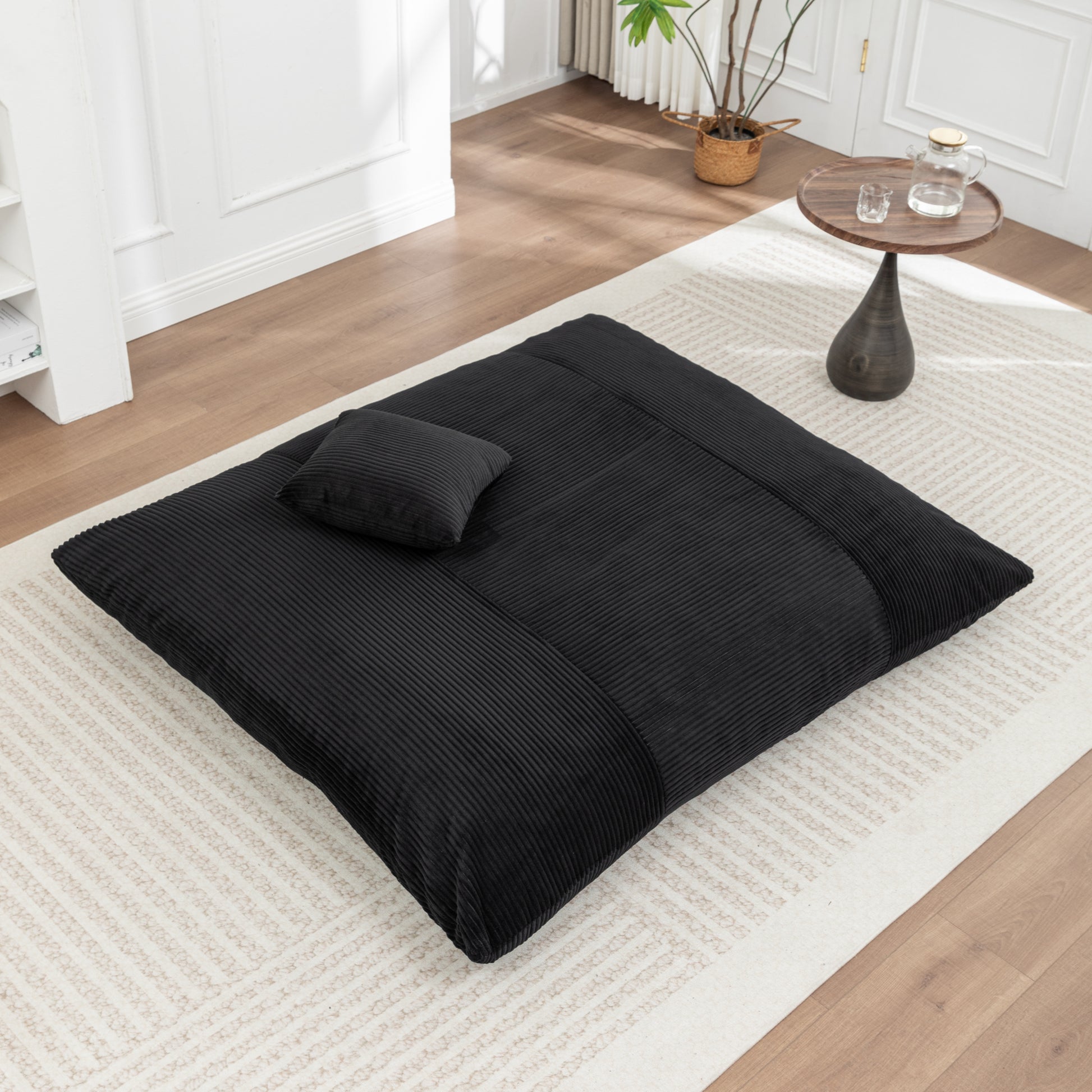 Floor bean bag chair in black corduroy fabric with pillow, displayed in a flat position for relaxing in any room.