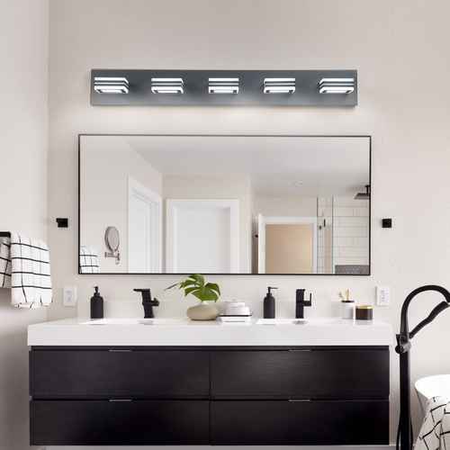 Bathroom vanity with mirror, lights, and various items on a neutral wall.