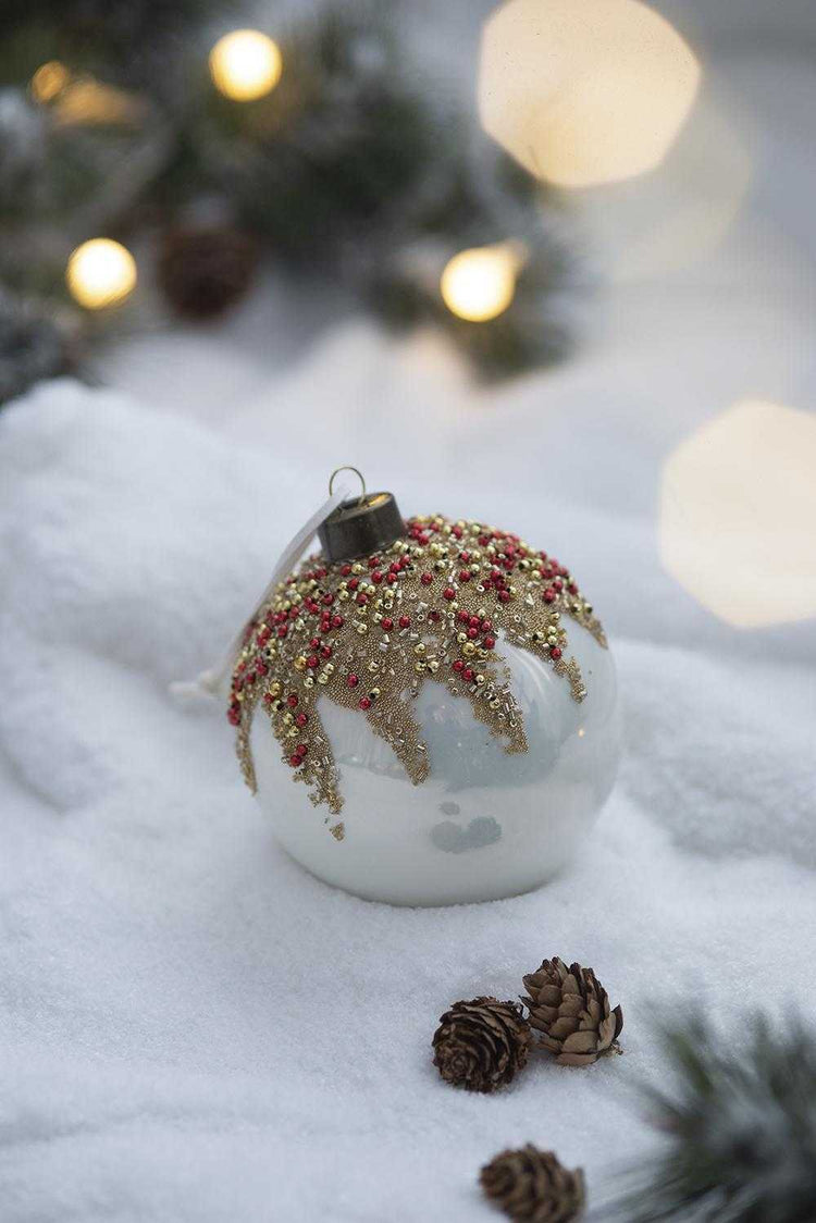 Decorative Christmas ornament on a snowy surface with blurred lights in the background