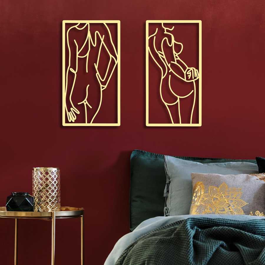 Two gold abstract wall art pieces on a red wall above a bed with decorative pillows.