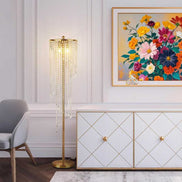 Tall gold floor lamp for living room placed next to a white and gold cabinet, enhancing luxury interior with crystal lighting design.