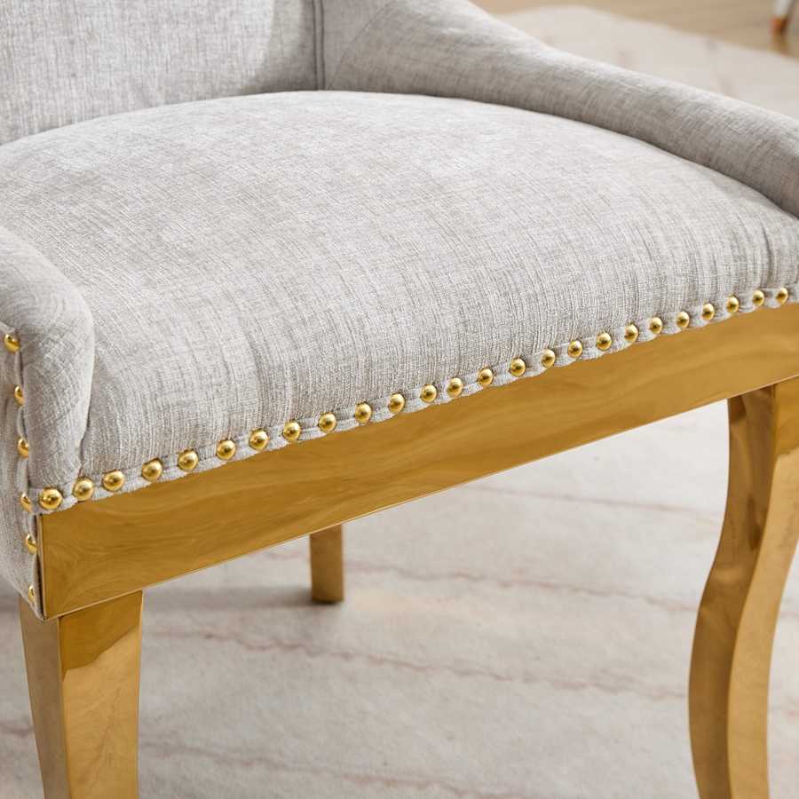 Chair with gray cushioned seat and gold nailhead trim on a light wooden frame.