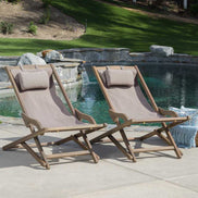 Two wooden lounge chairs with beige cushions by a poolside.