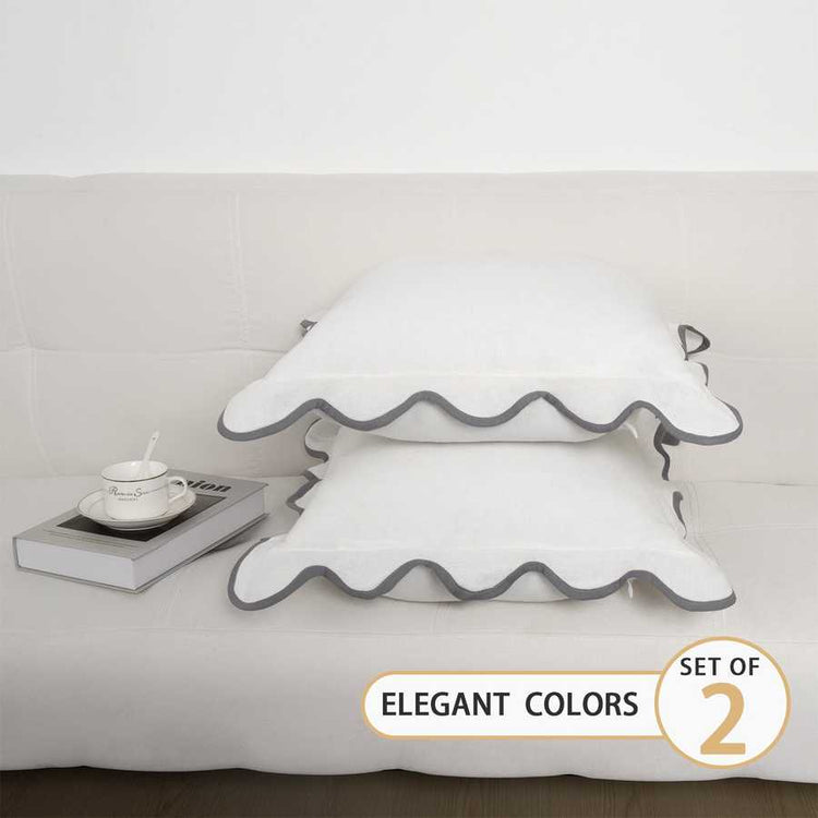 Set of two decorative pillows with ruffled edges on a bed, labeled &