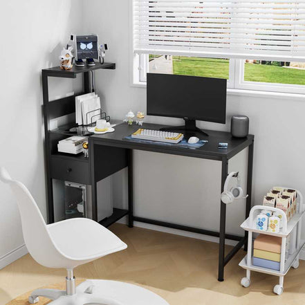 Computer desk with power outlet and USB ports in black, set up in a bright home office with reversible shelves and compact design.