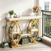 A gold console table with a white marble-patterned top and open shelves, styled in a bright entryway or balcony setting with plants, flowers, baskets, and decor.