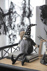 Whimsical Halloween decor set featuring a black gnome with a polka dot hat, long gray beard, sitting on books with spooky black web and bat decorations in the background.