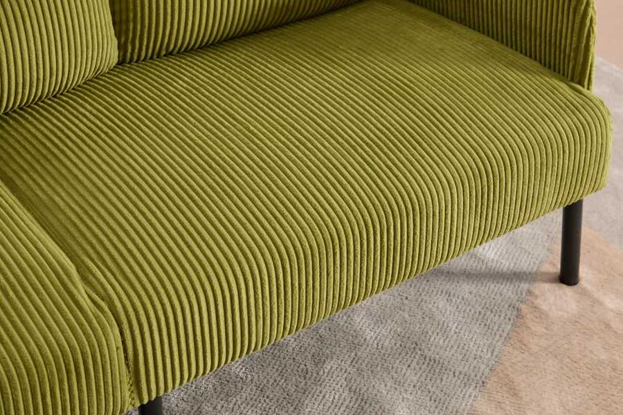 Close-up of a green ribbed sofa on a patterned floor.