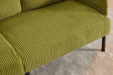 Close-up of a green ribbed sofa on a patterned floor.