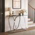 A modern console table with a black glass top and a polished silver metal frame featuring interlocking curved loops, styled in an entryway next to a staircase.