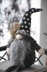 Gnome with tall polka dot hat, long beard, and striped legs, sitting outdoors with a wintery background, perfect for seasonal decoration