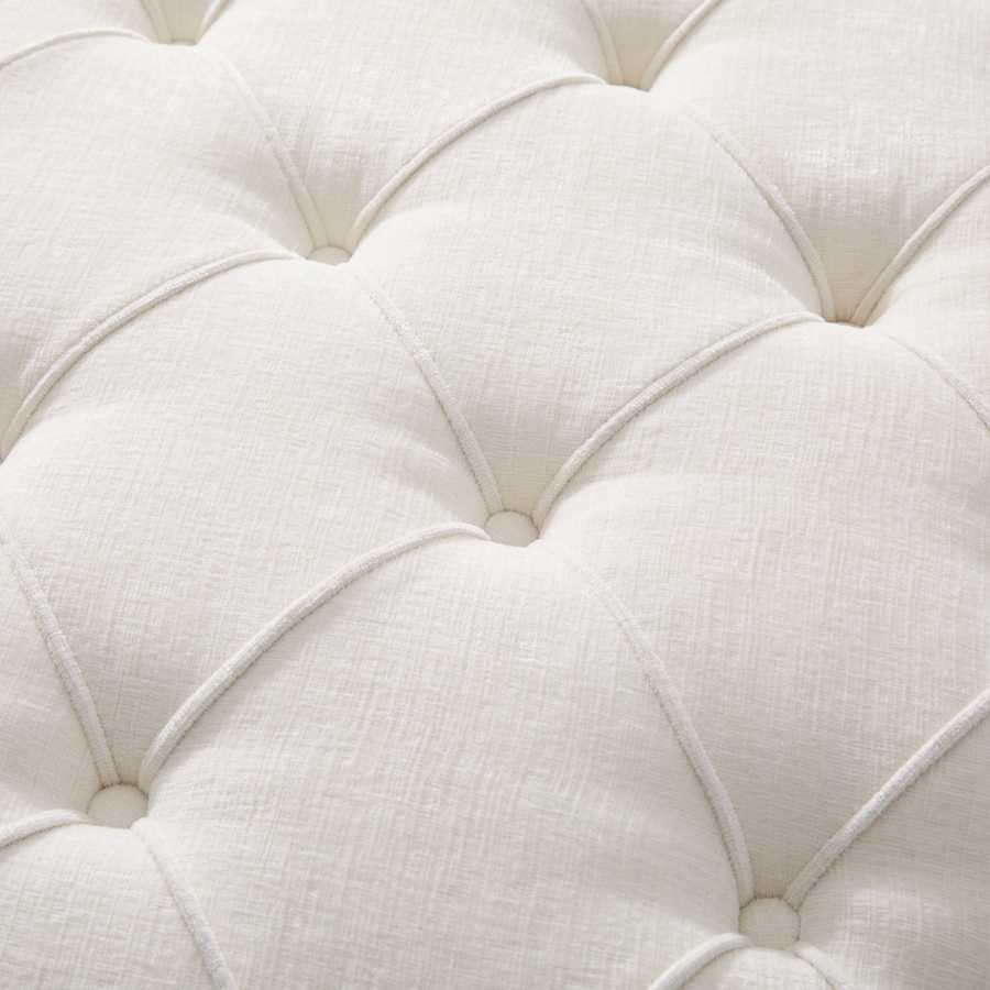 Close-up of a white tufted cushion with a soft texture