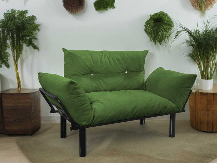 Green futon sofa in a room with plants and wooden furniture.