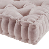 Close-up of a textured beige cushion with tufted design on a white background