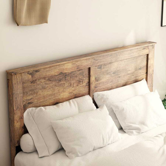 Close-up of rustic wood headboard on full size platform bed frame with white pillows, showcasing natural wood grain texture.