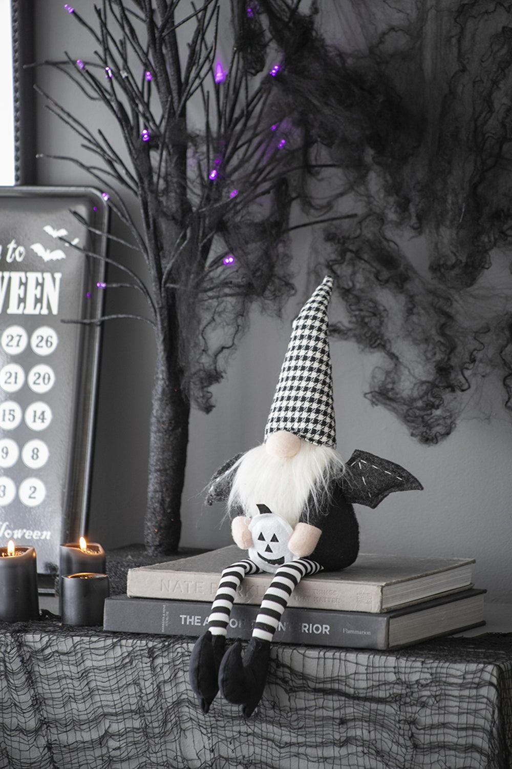 Halloween-themed decor with a ghostly figure, books, and candles on a dark background.
