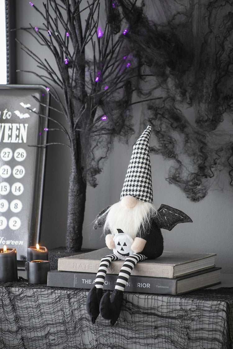 Halloween-themed decor with a ghostly figure, books, and candles on a dark background.