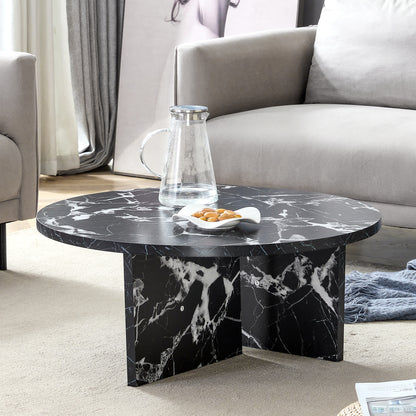 Modern minimalist black MDF round coffee table styled in a living room with faux marble surface and cross-leg base.