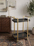 Stylish black and gold metal bar cart with two tiers, gold frame, black trays, and casters for easy movement in a modern living room