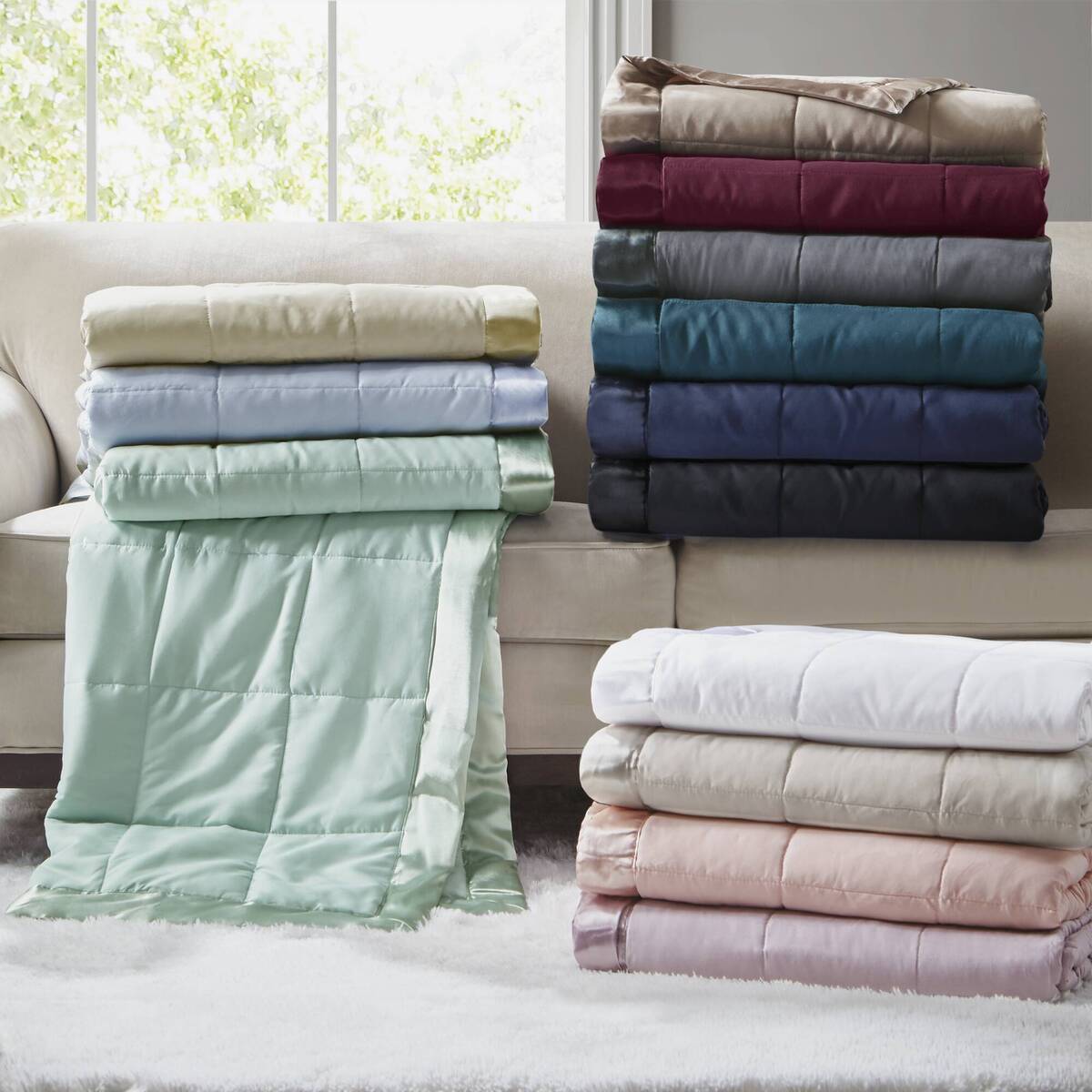 Stack of Lightweight Down Alternative Blankets in various colors on a sofa, showcasing color options for versatile home bedding decor.