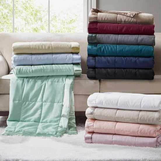 Stack of Lightweight Down Alternative Blankets in various colors on a sofa, showcasing color options for versatile home bedding decor.