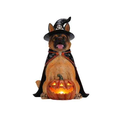 A Halloween decoration shaped like a German Shepherd dog dressed as a witch, wearing a black pointed hat with a skull emblem and a black cape with orange trim, sitting behind a glowing jack-o&