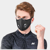 Person wearing a black face mask with valve on a gray background