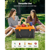 Two women sitting on grass with a cooler box containing food and drinks, text &