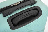 Close-up of a hard-shell suitcase in mint green with black telescoping handle and zipper pull.