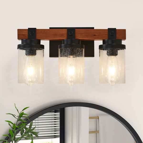 Three-light wall sconce with wooden frame and glass shades on a white wall.
