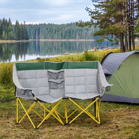 Camping chair with yellow legs and green and gray cover next to a tent by a lake.